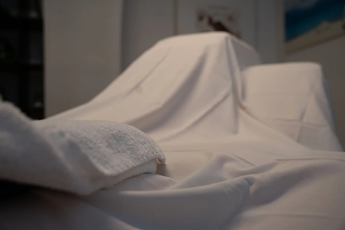 Nahaufnahme eines weißen Handtuchs und des Stoffbezugs auf Silvias Massageliege